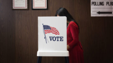 A photo of a person voting in a voting booth.